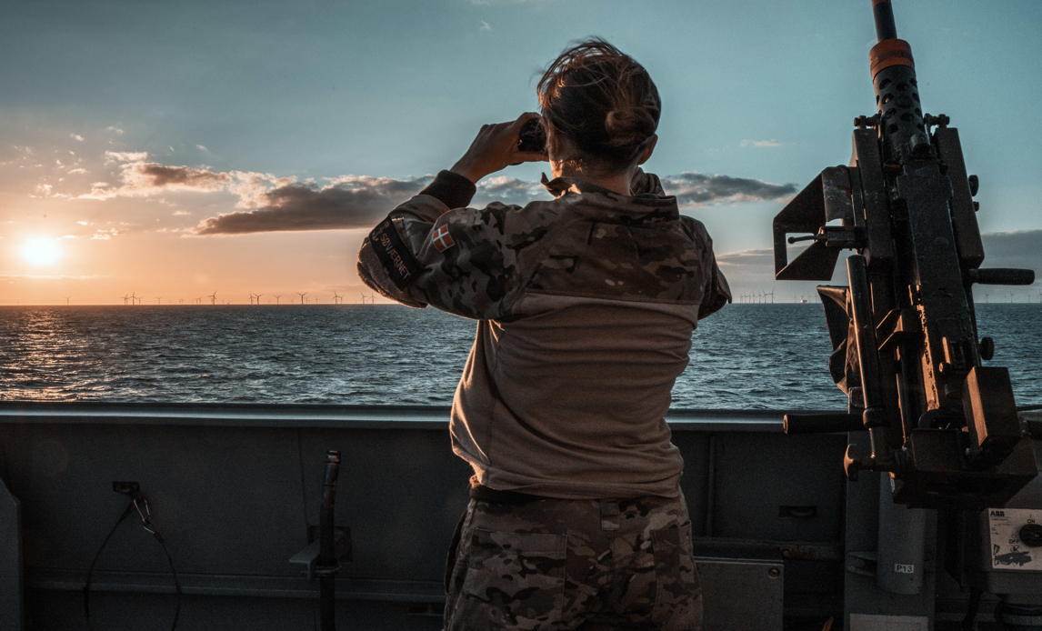 Soldat spejder ud over havet i sin kikkert