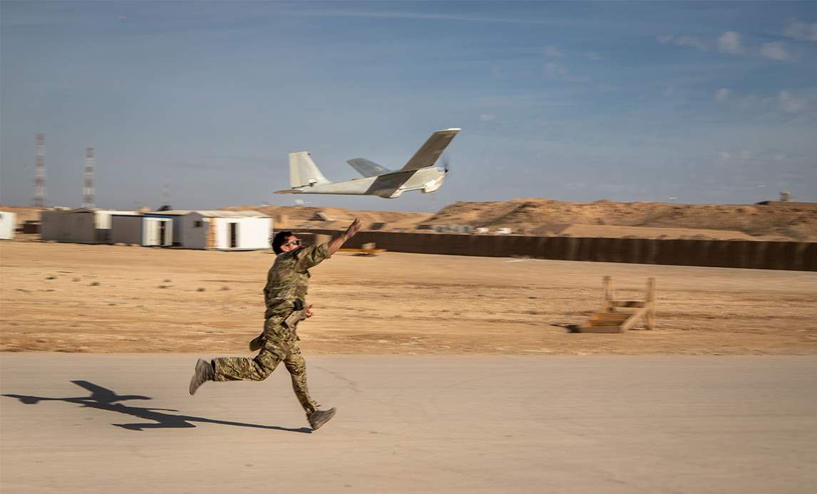 Det er den danske PUMA-drone, der hver eneste dag er på vingerne og sørger for sikkerheden omkring basen. ”Vores opgave er at overvåge området omkring basen for at imødegå trusler fra Islamisk Stat. Det gør vi ved hele tiden at observere området fra luften,” siger oversergent Morten, der er gruppefører for UASgruppen på Al Asad Airbase. Dronen er en amerikansk bygget PUMA AE. Den flyver i flere timer ad gangen og er typisk kun på jorden for at få skiftet batteri, inden den bliver sendt af sted igen.